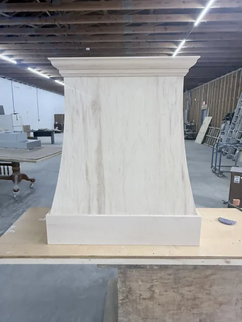 Custom curved wood range hood built in the Ocean Bay Interiors shop