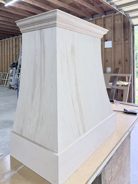 Custom curved wood range hood built in the Ocean Bay Interiors shop