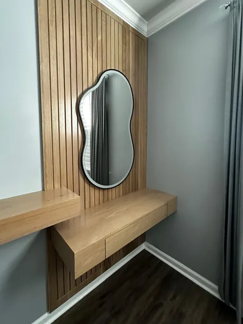 Custom oak slat wall with floating vanity shelf and backlit mirror