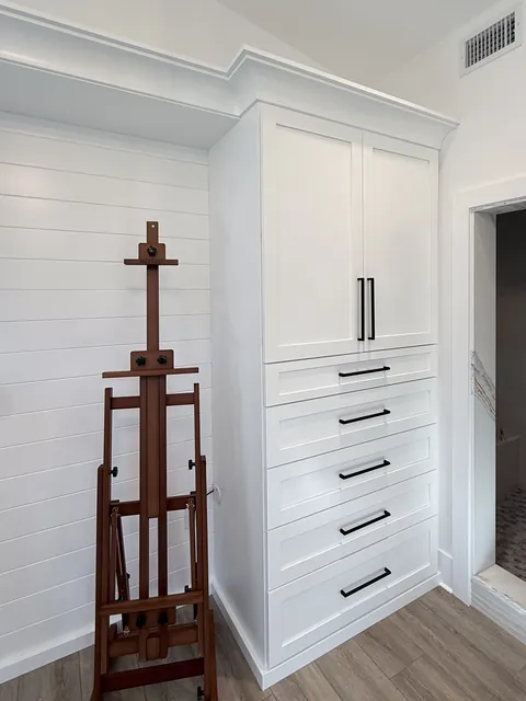White custom closet and entry cabinetry with a navy vanity