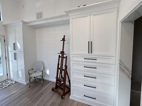 White custom closet and entry cabinetry with a navy vanity