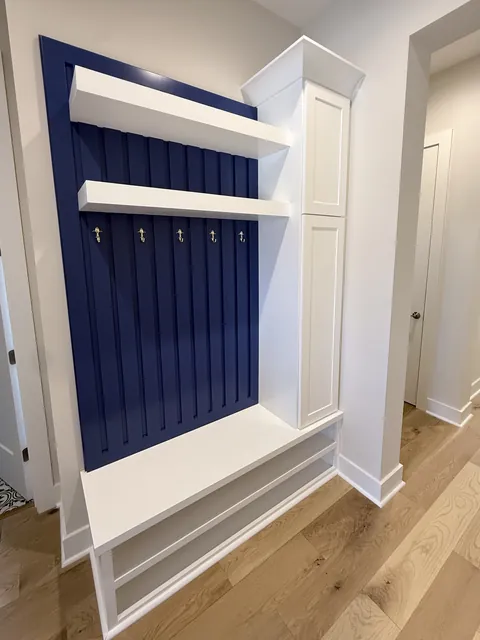 Custom mudroom bench with navy beadboard and storage cabinets