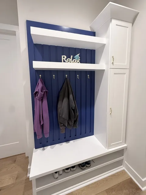 Custom mudroom bench with navy beadboard and storage cabinets