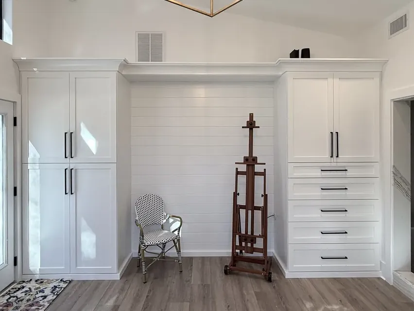 Custom white closet system with tall wardrobe doors and a bank of soft-close drawers